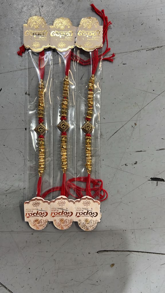 Elegant gold beaded rakhi set with red thread and ornamental design
