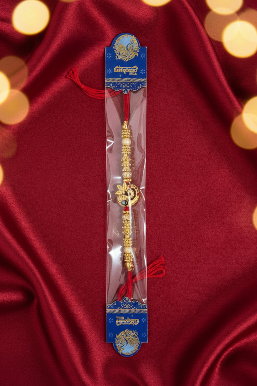 Gold peacock design rakhi with red thread and decorative beads