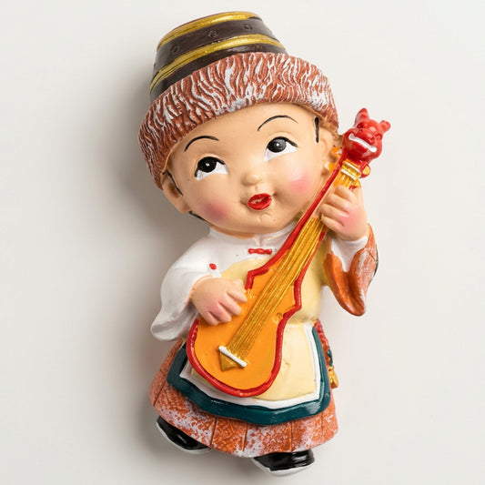 Colorful Nepali traditional musician ceramic fridge magnet featuring a cute doll holding a stringed musical instrument and wearing Himalayan-inspired clothing.