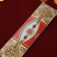 Red and gold floral rakhi with pearl beads and ornate centerpiece