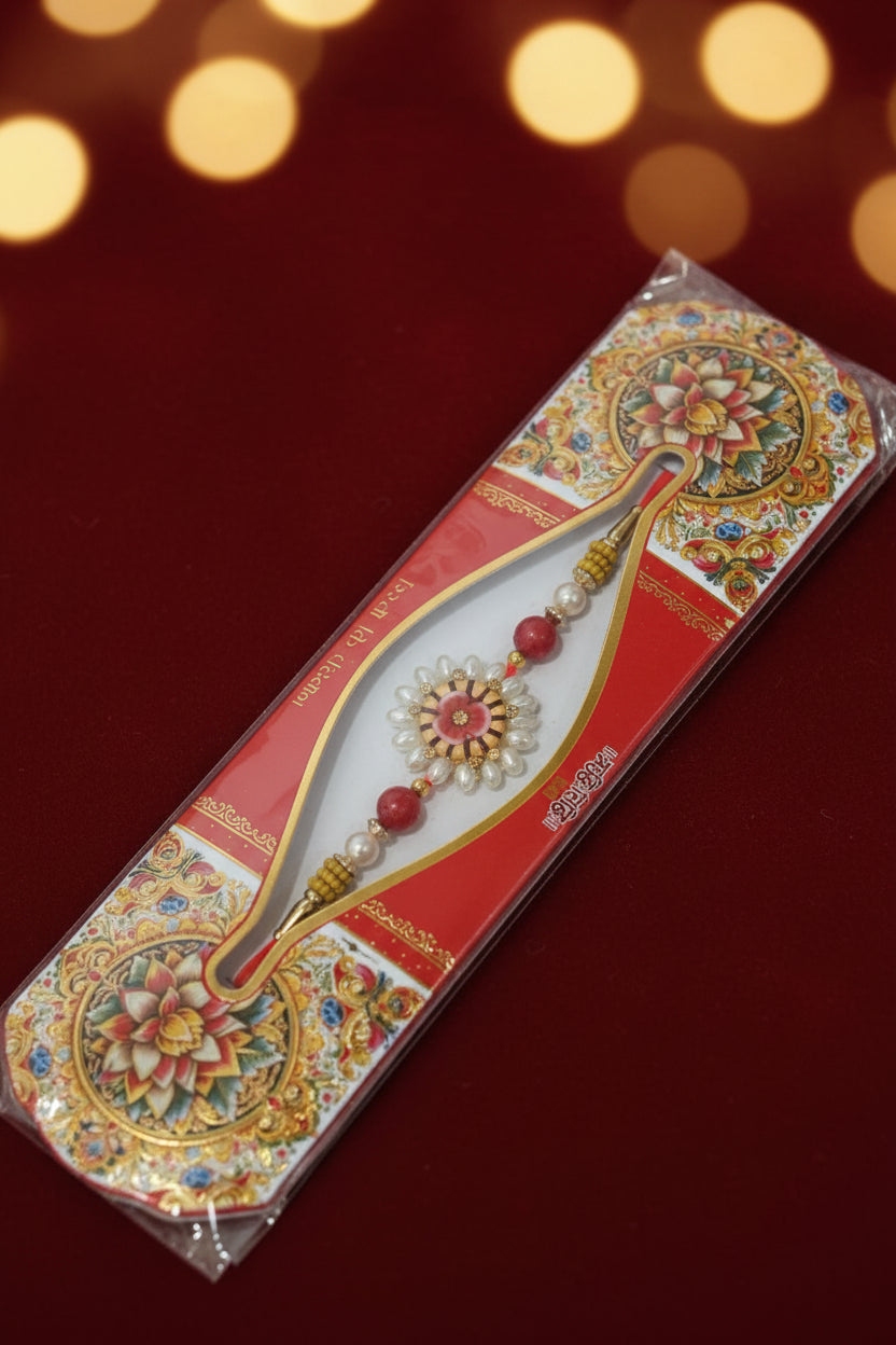 Red and gold floral rakhi with pearl beads and ornate centerpiece