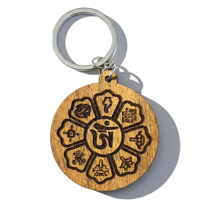 Round wooden Tibetan-inspired keychain with central Om symbol and engraved symbolic designs