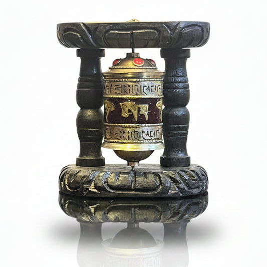 Tibetan Buddhist prayer wheel with Om Mani Padme Hum mantra and carved dark wooden display stand