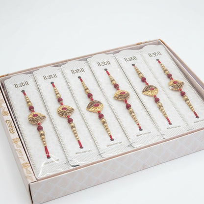 Elegant gold beaded rakhi set with red thread and ornamental design