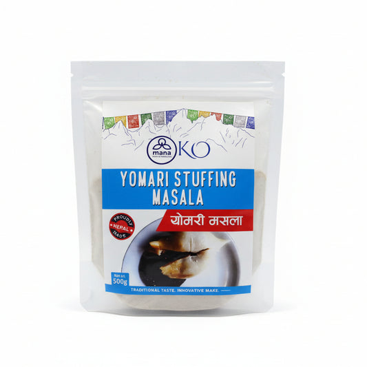 Front packaging of Mana KO Yomari Stuffing Masala 500g showing a sliced Yomari with rich dark filling.