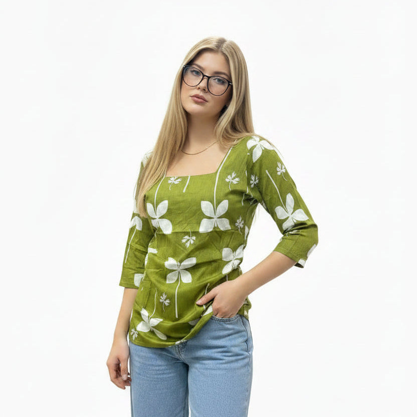 A woman wearing an olive green short kurti with a white clover print and square neckline, paired with blue jeans.